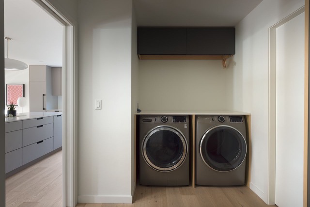 Laundry with grey washer and dryer beside the kitchen