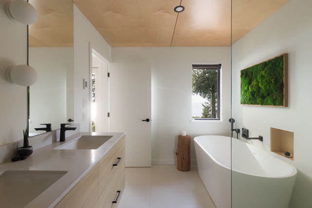 Bathroom after — oak double vanity, freestanding tub and moss wall art